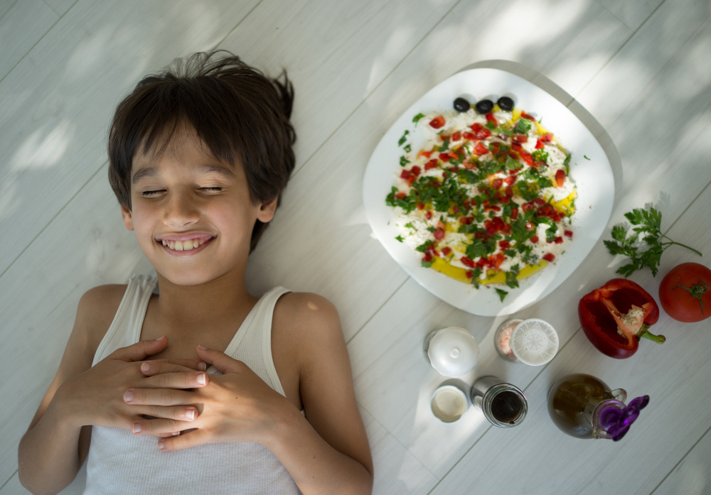 Kid enjoying summer organic kitchen preparing food with vegetable ingredients and creamy cheese